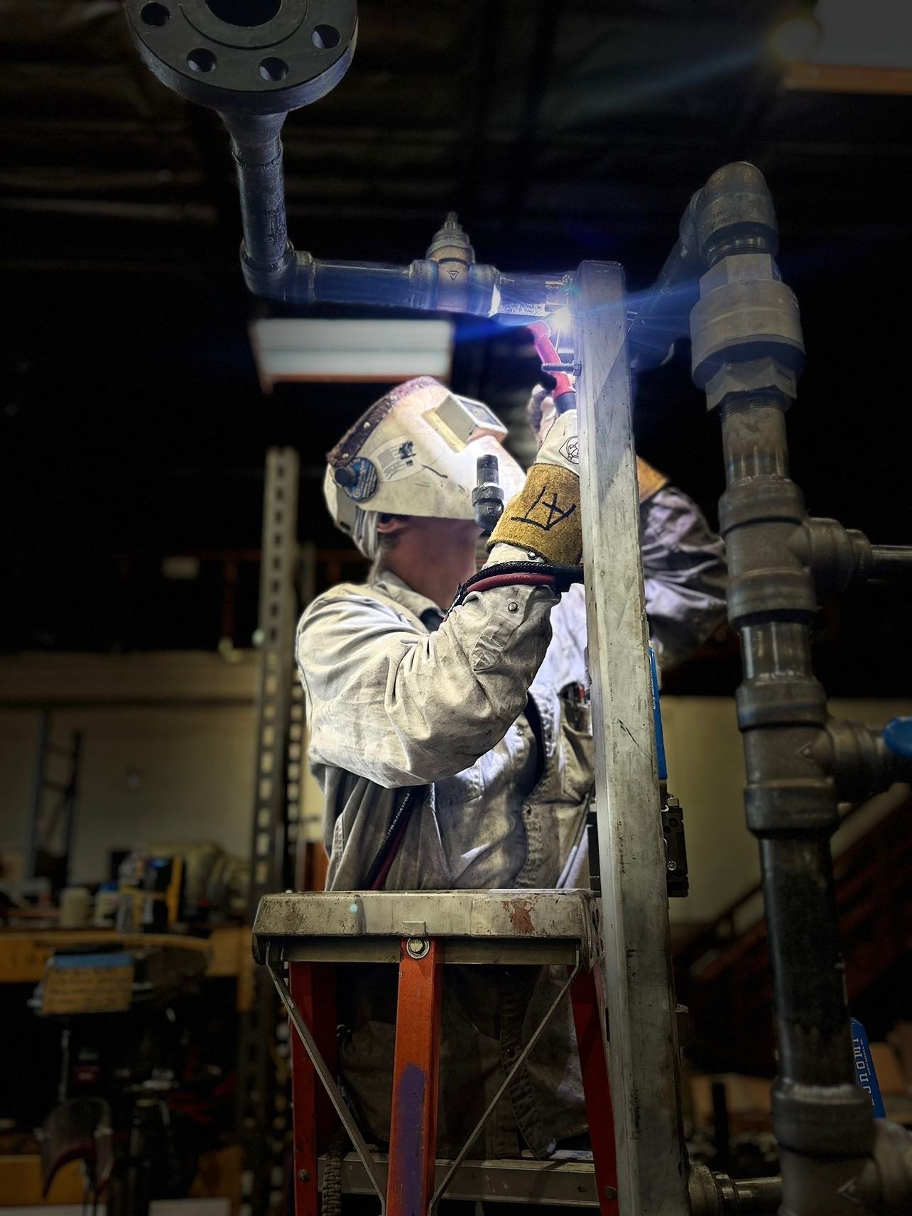 Welder fabricating pipe fittings with welding arc